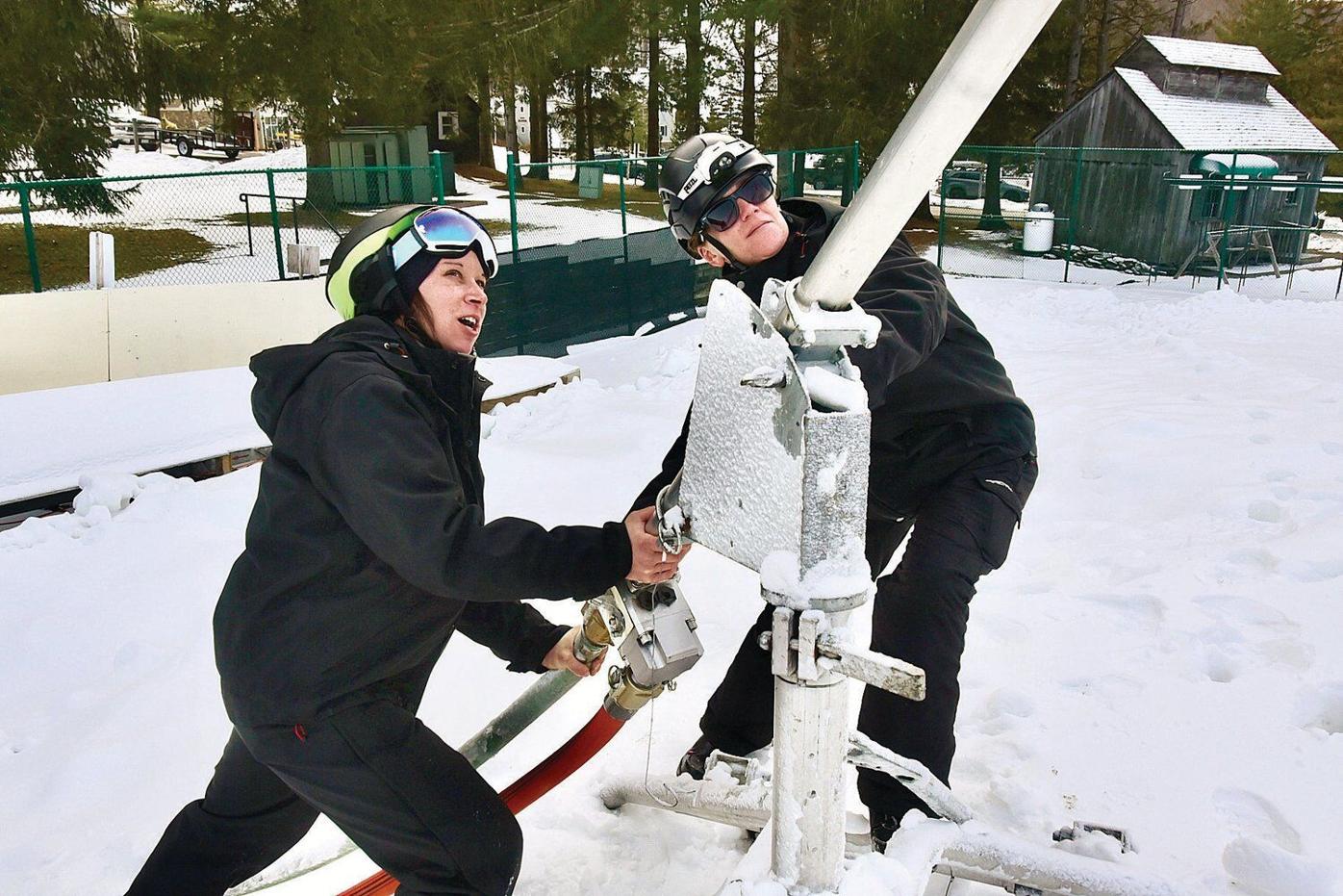 Two workers adjust snow gun