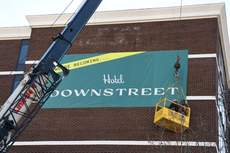 Men in a crane lift adher a new sign to the former Holiday Inn