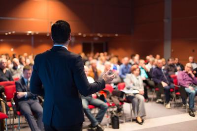 Man gesturing in front of meeting of people