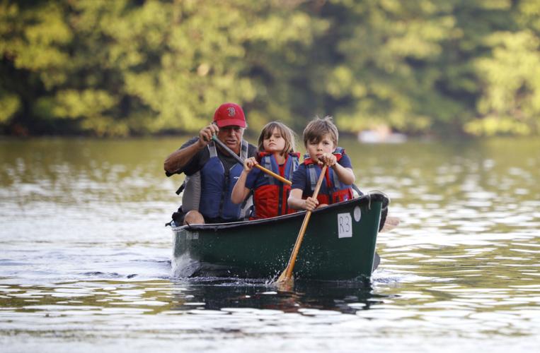 grandfather and two kids paddle in canoe