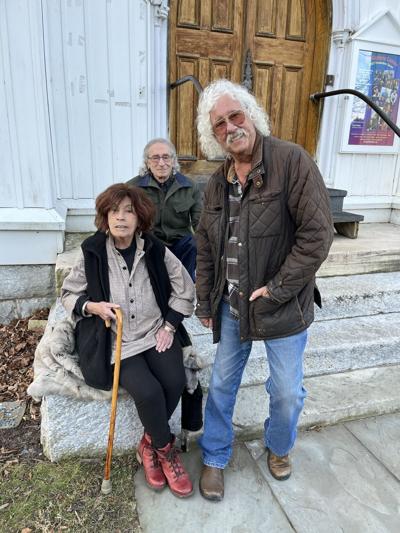 Alice Brock, Rick Robbins and Arlo Guthrie stand outside a building in Great Barrington