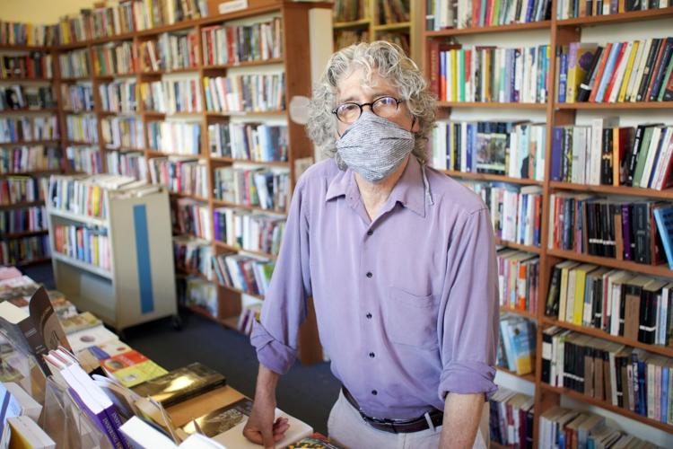 Man wearing mask standing in front of bookshelves