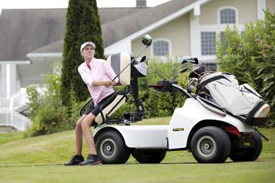 woman sitting on adaptive golf cart after teeing off