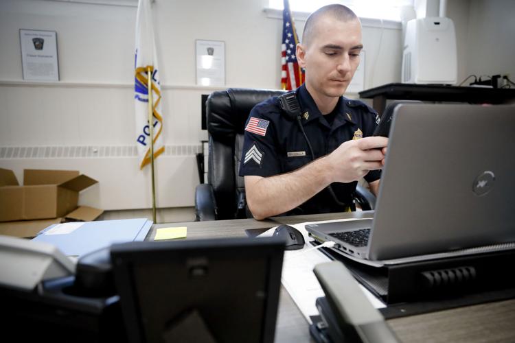 Police officer sitting at a desk texting in front of computer