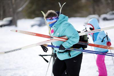Woman carrying skis and poles with child