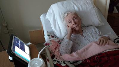An elderly woman lies in a hospital bed