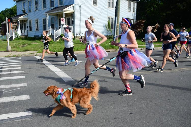 A dog runs with women runners in tutus