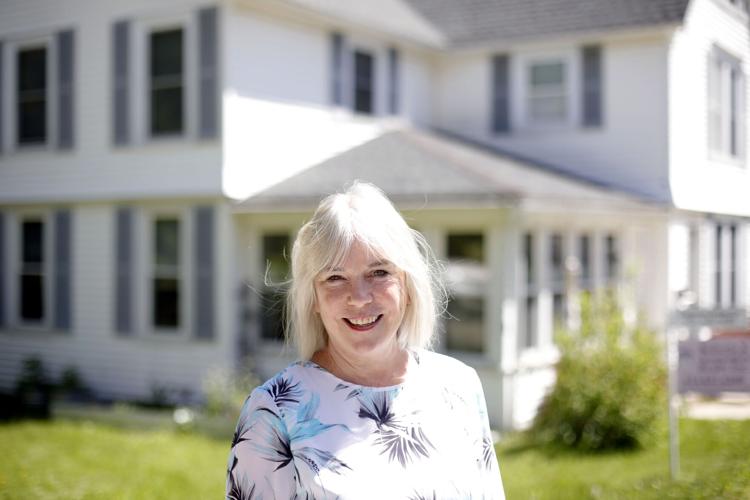 Realtor Pam Roberts smiles in front of house