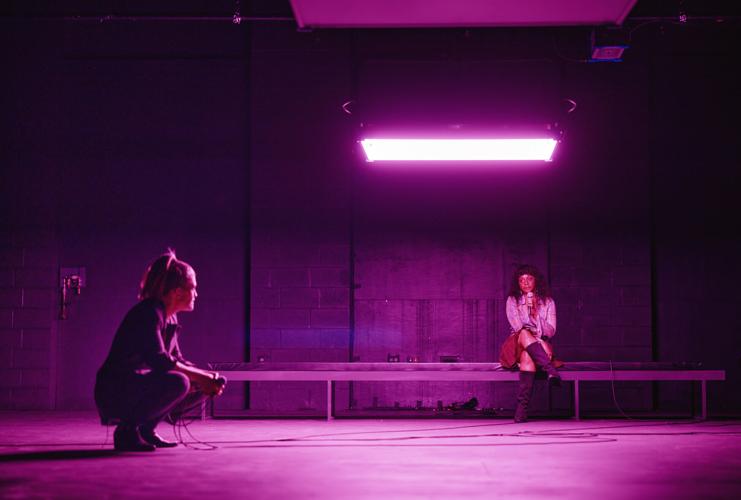 Two women on a stage in purple light