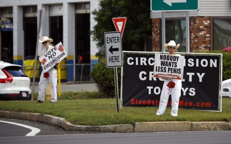 man and woman in white with red stain on pants protesting circumcision
