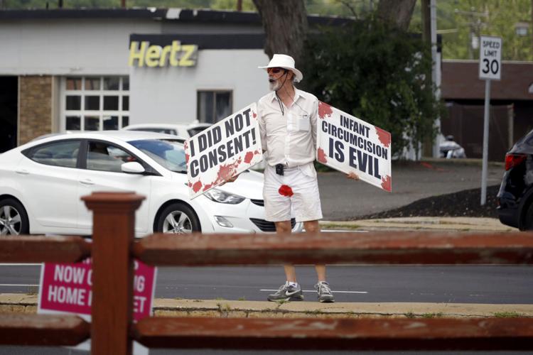 man in white with red stain on pants protesting circumcision