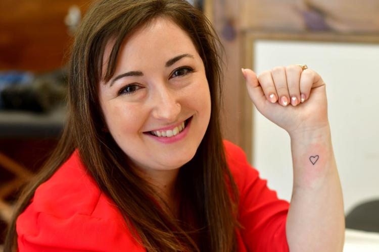 A woman poses with a heart tattoo on her arm
