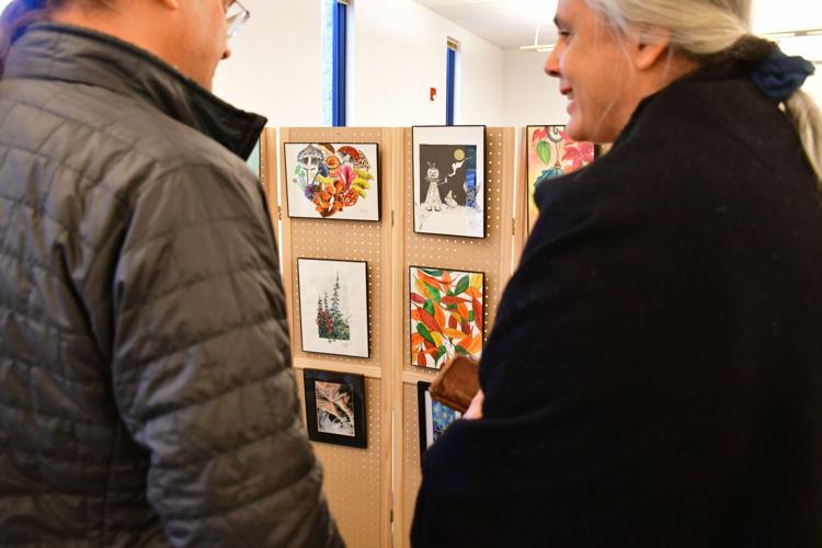 People look at artwork as they shop at a holiday market
