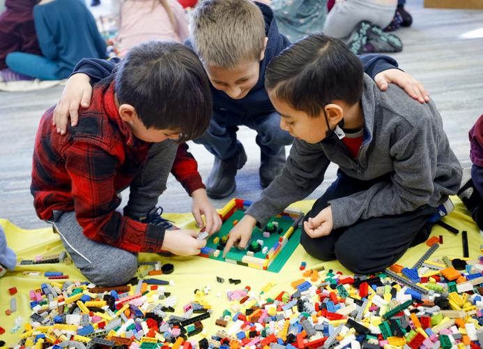 three boys work together on lego building