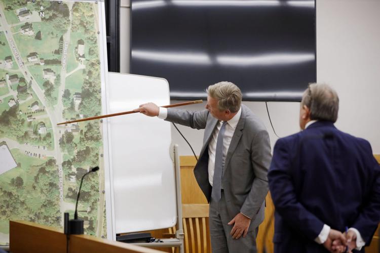 man points on map with long stick in courtroom