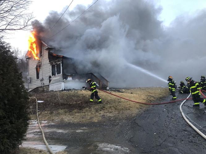 Fireghters spray water on burning home