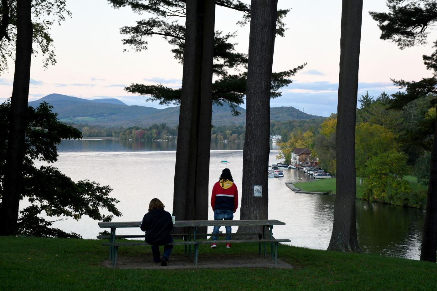 Two people look at Pontoosuc Lake through the trees
