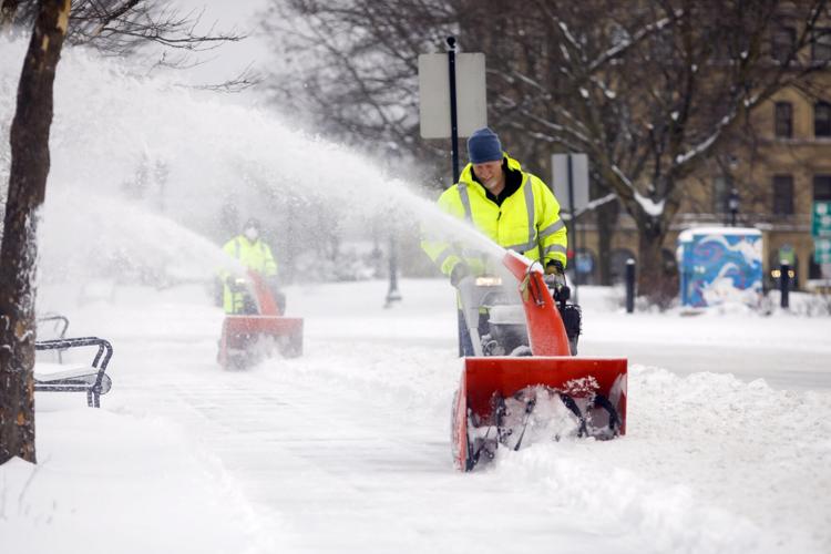snowblowers woring together clearing sidewalk