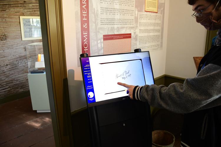 A docent points at a signature on the interactive kiosk