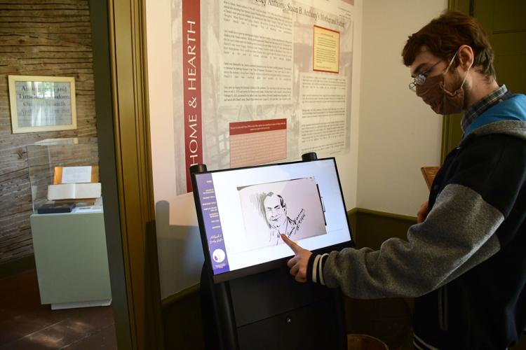A docent points at a signature on the interactive kiosk