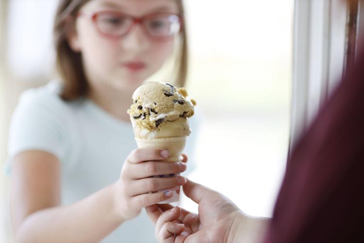 girl takes ice cream cone at window