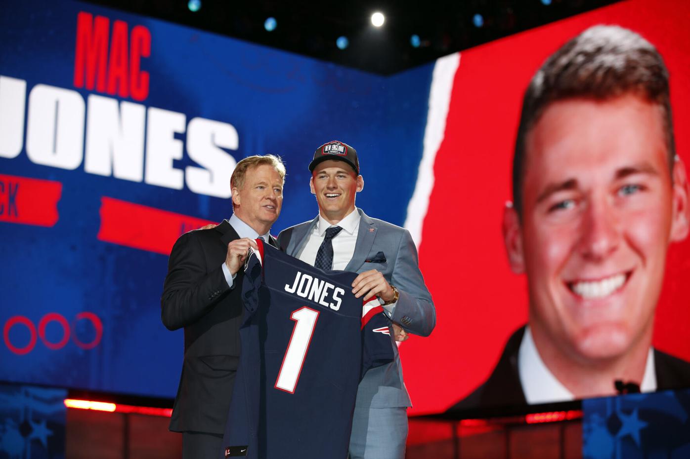 Alabama quarterback Mac Jones, right, holds a team jersey with NFL  Commissioner Roger Goodell a …