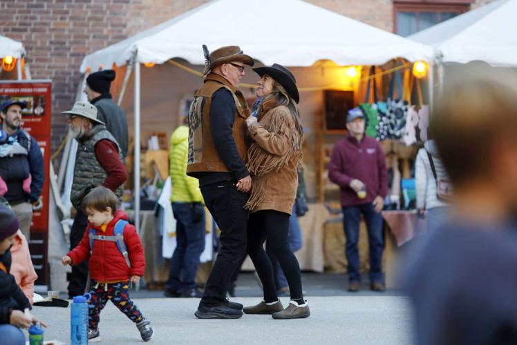 couple in brown suede jackets dance at music festival