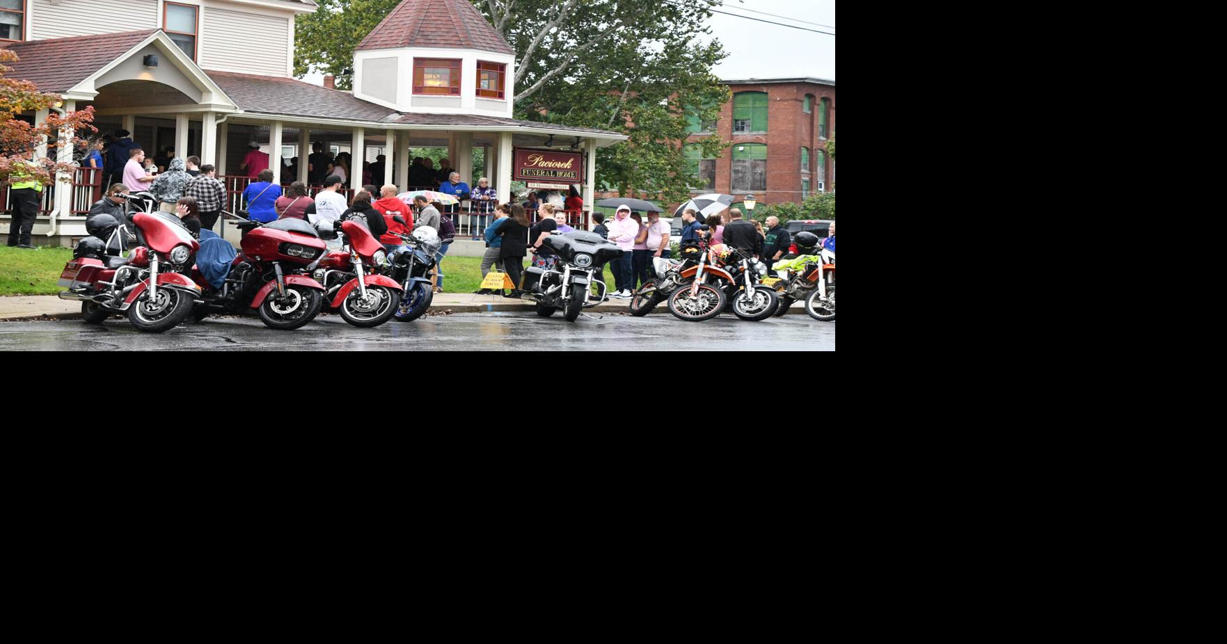 A funeral home with people and motorcycles parked out front