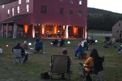 People sit in lawn chairs listening to musicians
