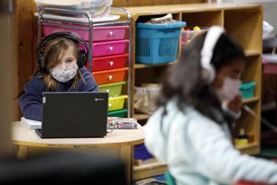 girl wearing mask and headphones looking at laptop