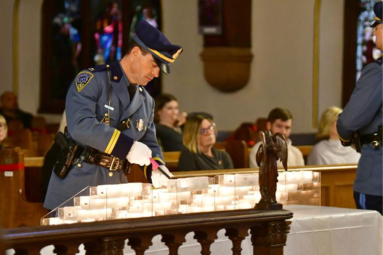 A state police officer lights a candle