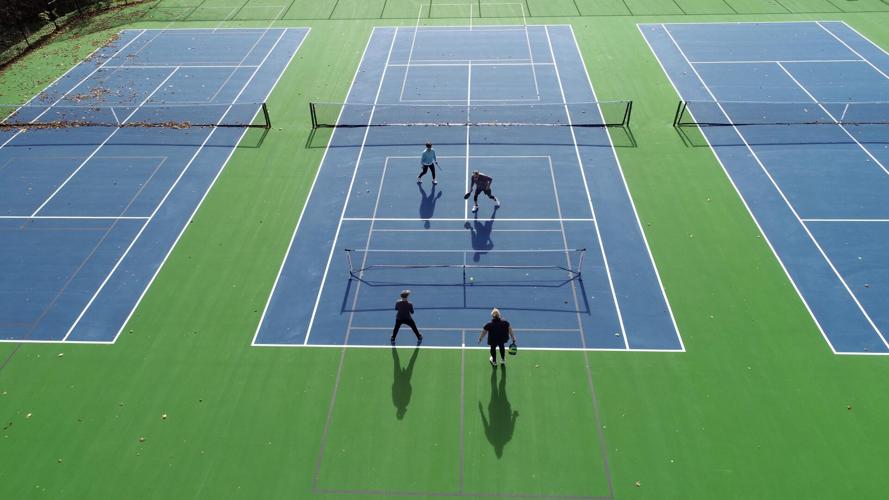Overhead view of pickleball players on bright green and blue tennis court
