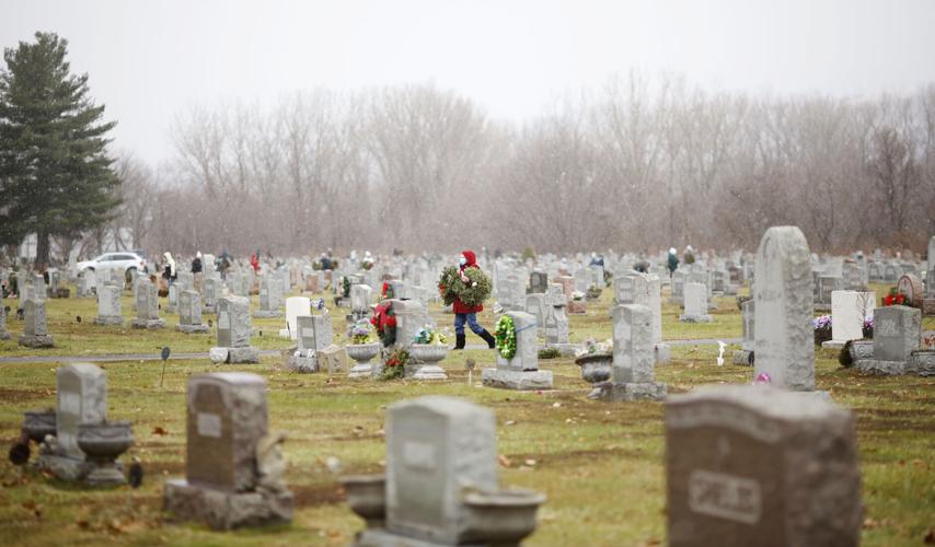 Volunteer placing wreaths in cemetery for Wreaths Across America