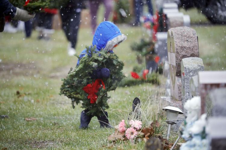 Jack Schutz places a wreath at a grave