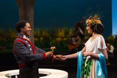 A man in a blue coat offers a flower to a woman in a white dress