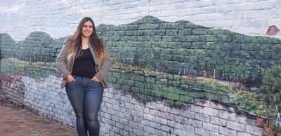Deanna Morrow smiles in front of a mural of a mountain