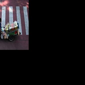 A street vendor pushes a cart of fresh fruit in Bangkok, where tighter controls on vendors threaten livelihoods and the street food culture that defines the Thai capital