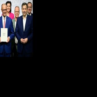 German Chancellor Friedrich Merz (C) poses with his cabinet after signing a coalition deal to form the country's new...