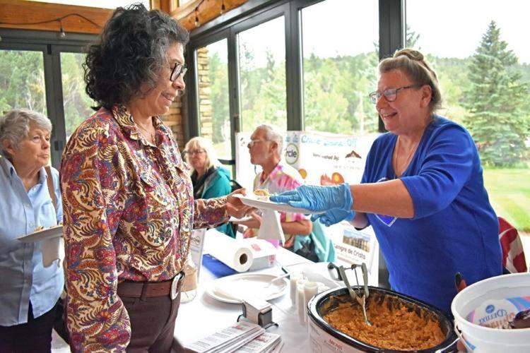Janine Giles serves a sample of her taco macarone and cheese dish to Marian Finn