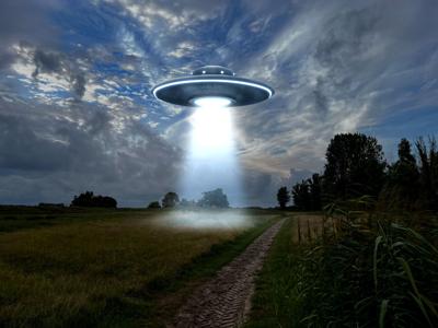 Alien spaceship emitting light beam over countryside. (AI image created by New Africa for Shutterstock)