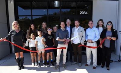 Performance Sock Company Feetures Ribbon Cutting. John Gaither cuts red ribbon with large scissors for new distribution center opening.