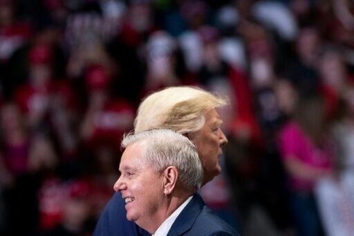 Senator Lindsey Graham (R-SC) arrives to speak with US President Donald Trump (R) during a rally at Bojangles' Coliseum in 2020