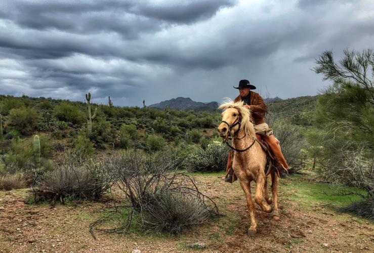 A rider from the Hashknife Pony Express gallops through the desert under stormy skies.