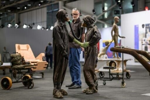 Un visitante de Art Basel observa de cerca una parte de 'El viaje: una marcha hacia la utopía', de Atelier Van Lieshout