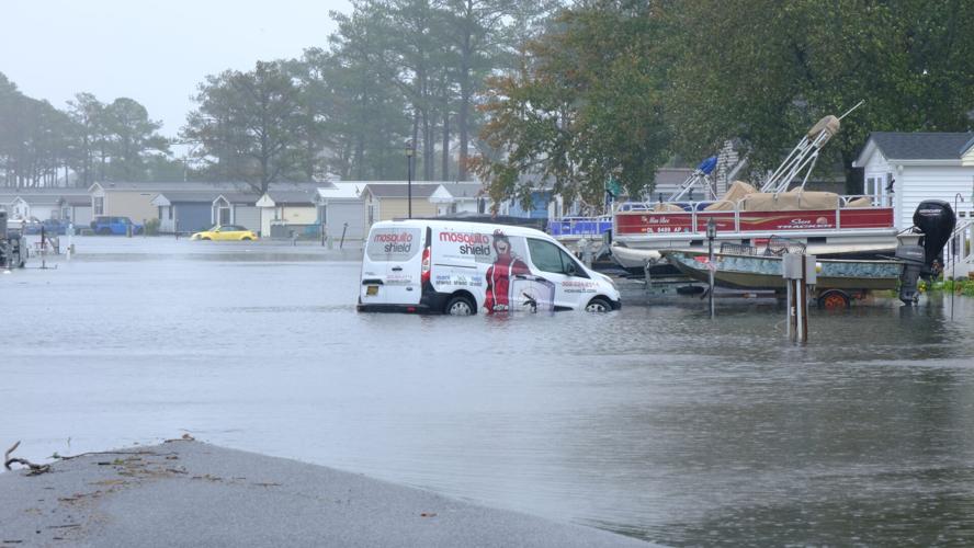 White cleaning van sitting in a road with water up to the top of its wheels.