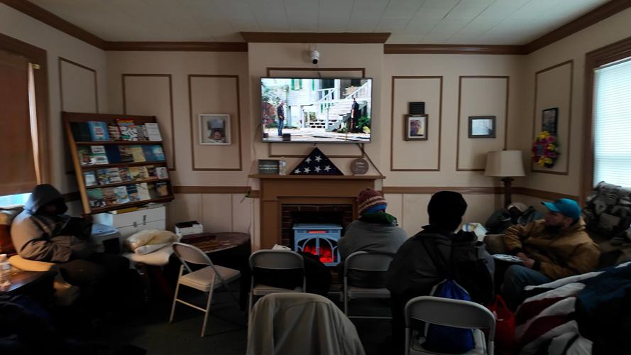 Homeless people warming up watching a movie at Higher Ground Outreach