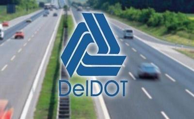 An image of cars driving on a divided highway with the DelDOT logo over the top of that in the middle of the picture.