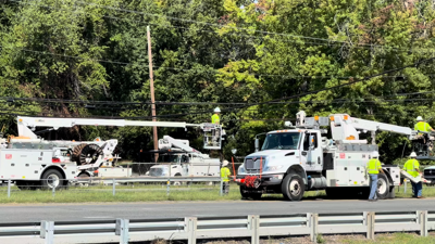 Utility workers line the highway to fix the downed poles and wires.