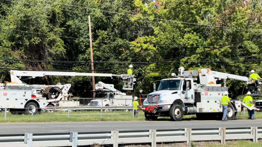 Utility workers line the highway to fix the downed poles and wires.
