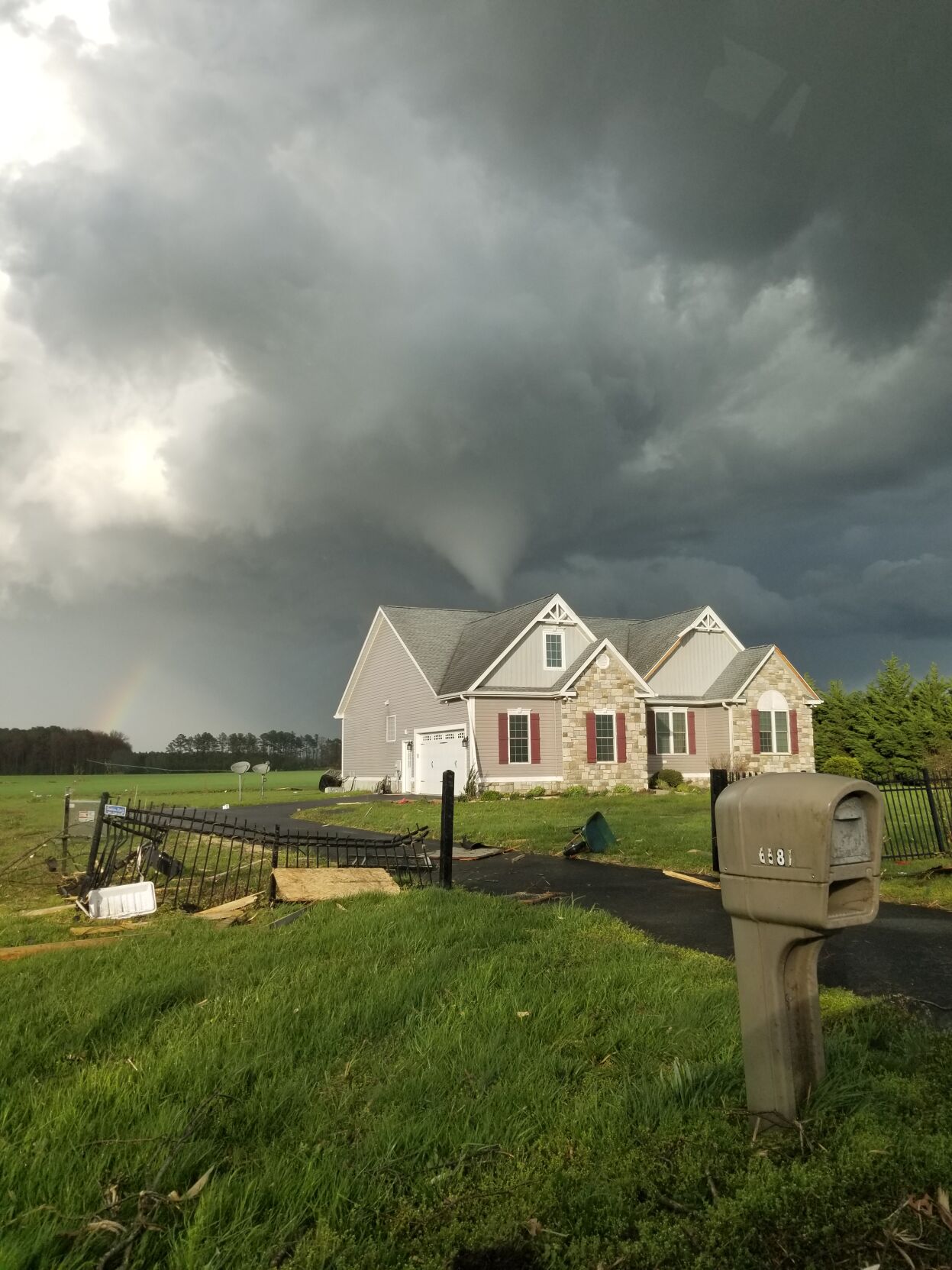 A home near Seashore Highway around 6 p.m. Saturday. The tornado's funnel can be seen behind the house and a rainbow on the left. Wind damaged the fence in the forefront.